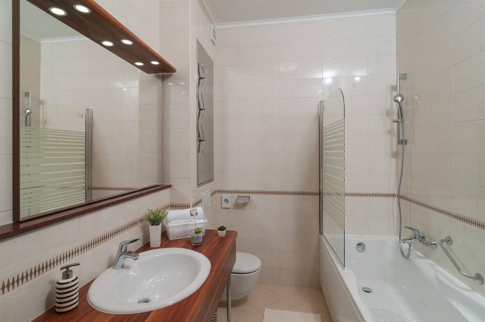 Bathroom with a bathtub, glass screen and wooden vanity