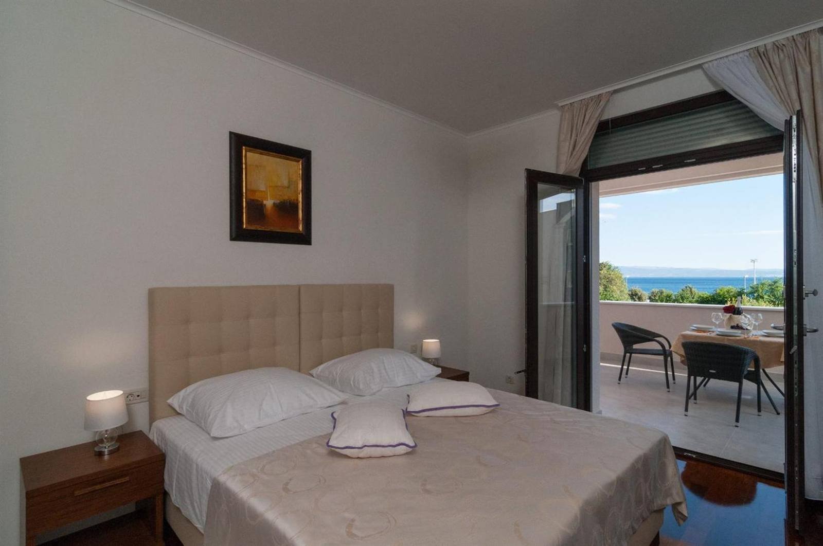 Bed with a headboard and an open balcony door facing the sea