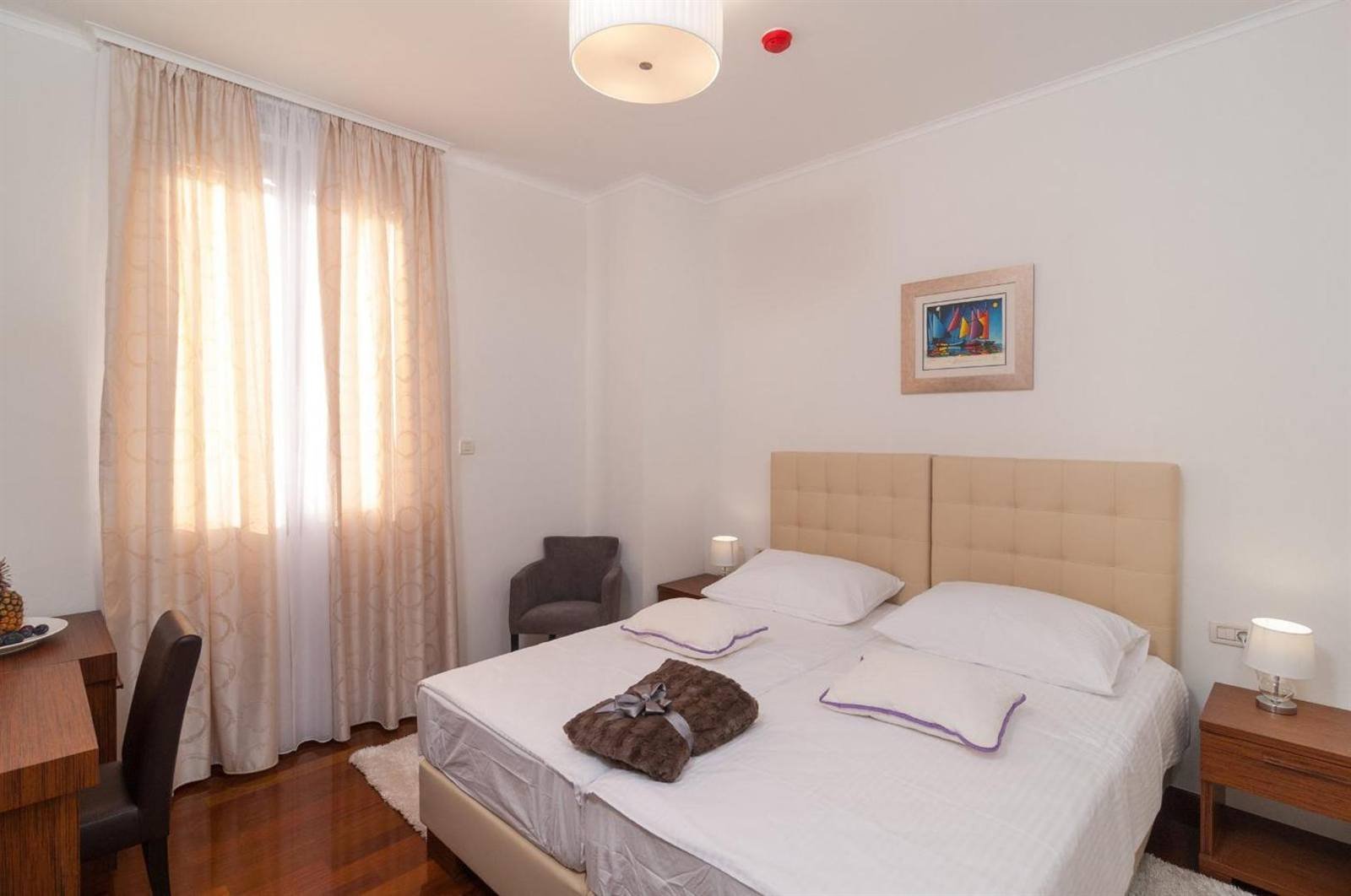 Double room with curtains, armchair and a bathrobe on the bed
